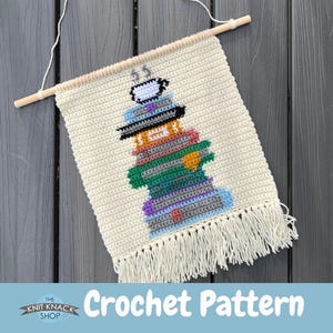 May include: A crochet pattern for a stack of books with a sheep on top. The pattern is on a white background with a fringe border. The text "Crochet Pattern" is at the bottom of the image.