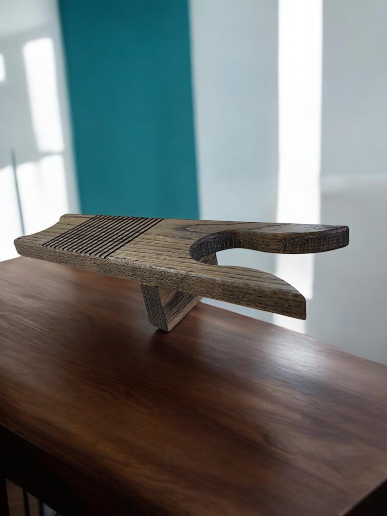 May include: Wooden tea tray with a unique design. The tray is made of light brown wood and features a slatted top surface and a curved handle. The tray is supported by a triangular base, and is designed for serving tea or other beverages.