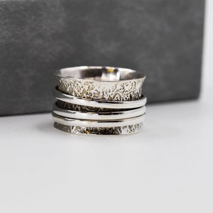 May include: A silver spinning ring with a textured band and multiple bands stacked on top of each other.