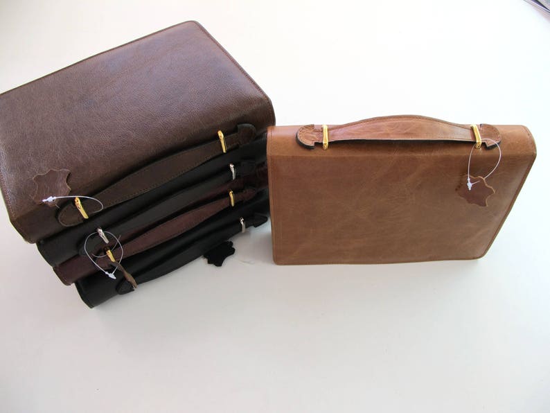 May include: A stack of five brown leather-bound journals with gold clasps and a single brown leather journal with a gold handle.