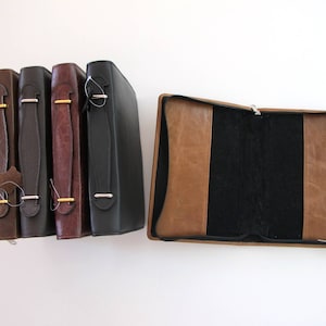 May include: Four brown leather-bound journals with gold accents and a single brown leather-bound journal with a black interior.