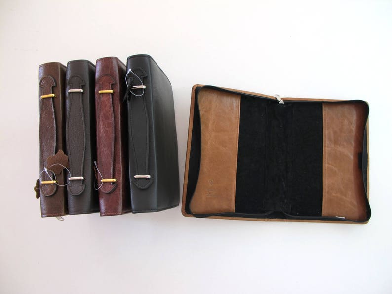 May include: Four brown leather-bound journals with gold accents and a single brown leather-bound journal with a black interior.