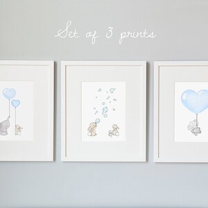 May include: Set of 3 framed prints featuring watercolor illustrations. One print shows an elephant and a smaller animal holding blue heart-shaped balloons. Another depicts bunnies with bubbles. The third shows an elephant holding a heart balloon.