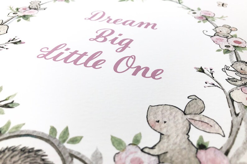 May include: A white card with a pink floral border and the text "Dream Big Little One" in pink script. The card features a watercolor illustration of a rabbit and a hedgehog.