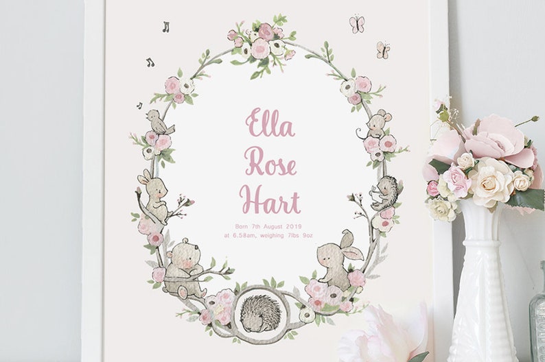 May include: A floral wreath with a pink background and a white border. The wreath is made of branches with pink flowers and leaves. There are small animals in the wreath, including a bird, a rabbit, a bear, a hedgehog, and a mouse. The text "Ella Rose Hart" is in the center of the wreath, along with the text "Born 7th August 2019 at 6.58am, weighing 7lbs 8oz."