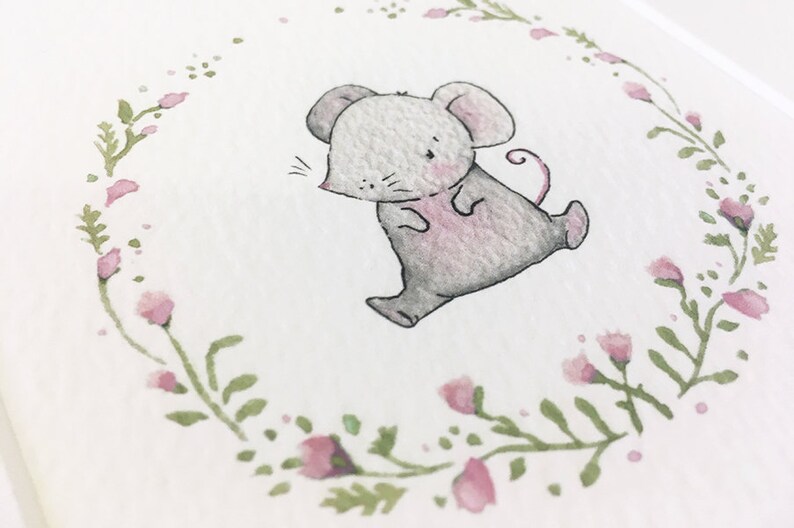 May include: A watercolor illustration of a cute gray mouse with pink accents, walking inside a wreath of green leaves and pink flowers.