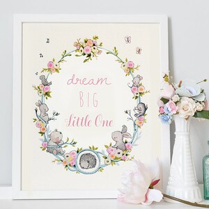 May include: A white framed print with a floral wreath and the text "dream big little one". The wreath is made of flowers, leaves, and small animals. The print is on a white background.