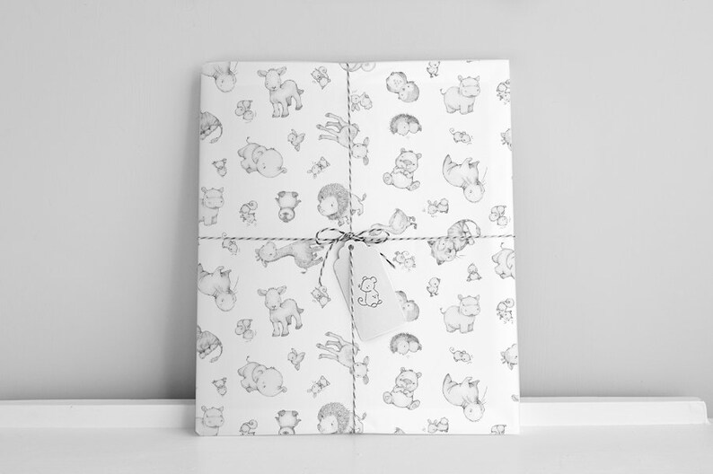 May include: White gift wrap with a black and white pattern of various animals, including a giraffe, a lion, a hippopotamus, and a goat. The gift wrap is tied with a brown string and a white tag with a black and white drawing of a bear.