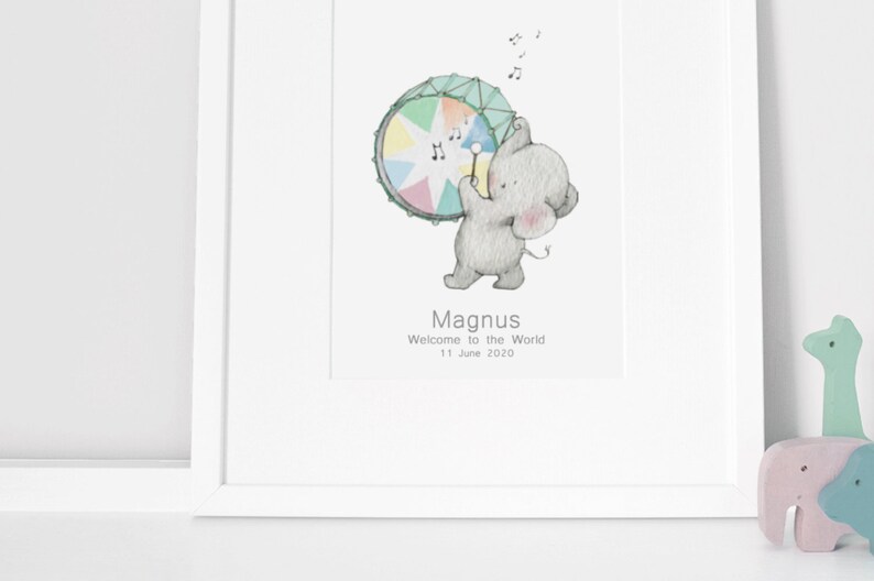 May include: A watercolor illustration of a gray elephant playing a rainbow drum with musical notes above. The text below reads "Magnus Welcome to the World 11 June 2020".