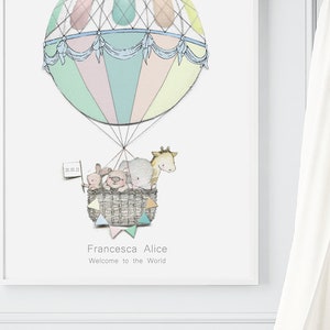 May include: A pastel-colored hot air balloon with a blue and white striped canopy carries a basket of stuffed animals, including a giraffe, elephant, pig, and bunny. The balloon is decorated with white string and a banner that reads "Francesca Alice Welcome to the World".