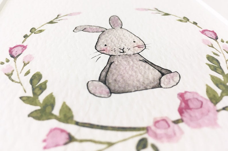 May include: A watercolor painting of a gray bunny sitting in a wreath of pink flowers and green leaves.