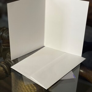 Peut inclure: Une carte blanche avec une enveloppe blanche. La carte est pli&eacute;e en deux et l'enveloppe est pos&eacute;e dessus.