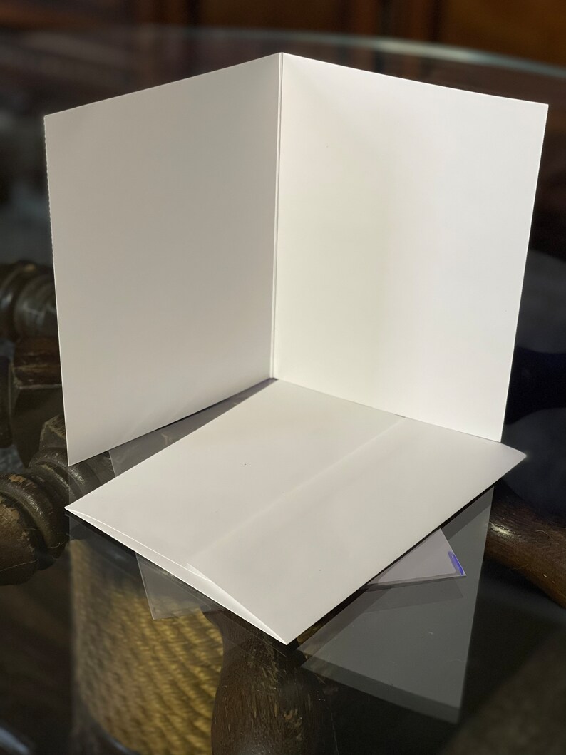 Peut inclure: Une carte blanche avec une enveloppe blanche. La carte est pli&eacute;e en deux et l'enveloppe est pos&eacute;e dessus.