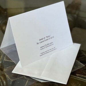 Peut inclure: Une carte blanche avec le texte "Detail of: "Ruby" By: Laura Curtin &copy; 2019 www.LCurtin.com Design by: NiceGraphix.com Property cared for, this card will maintain its brilliance for generations."