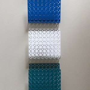 May include: Five metal magazine holders in different colors: gray, blue, white, teal, and yellow. Each holder has a geometric pattern.