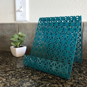 May include: Teal metal magazine holder with a geometric pattern. The holder is standing on a granite countertop.