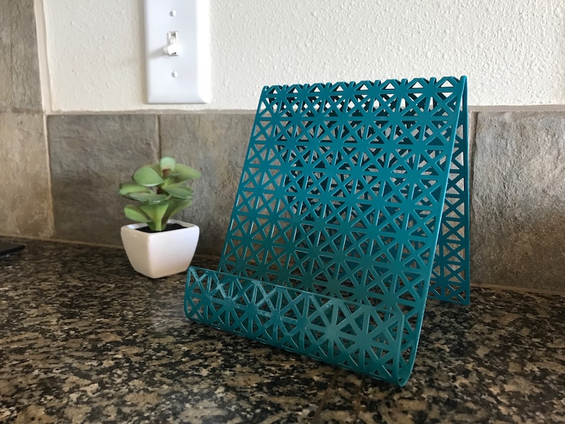 May include: Teal metal magazine holder with a geometric pattern. The holder is standing on a granite countertop.