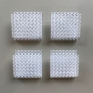 May include: Four white metal wall mounted magazine holders with a geometric pattern.