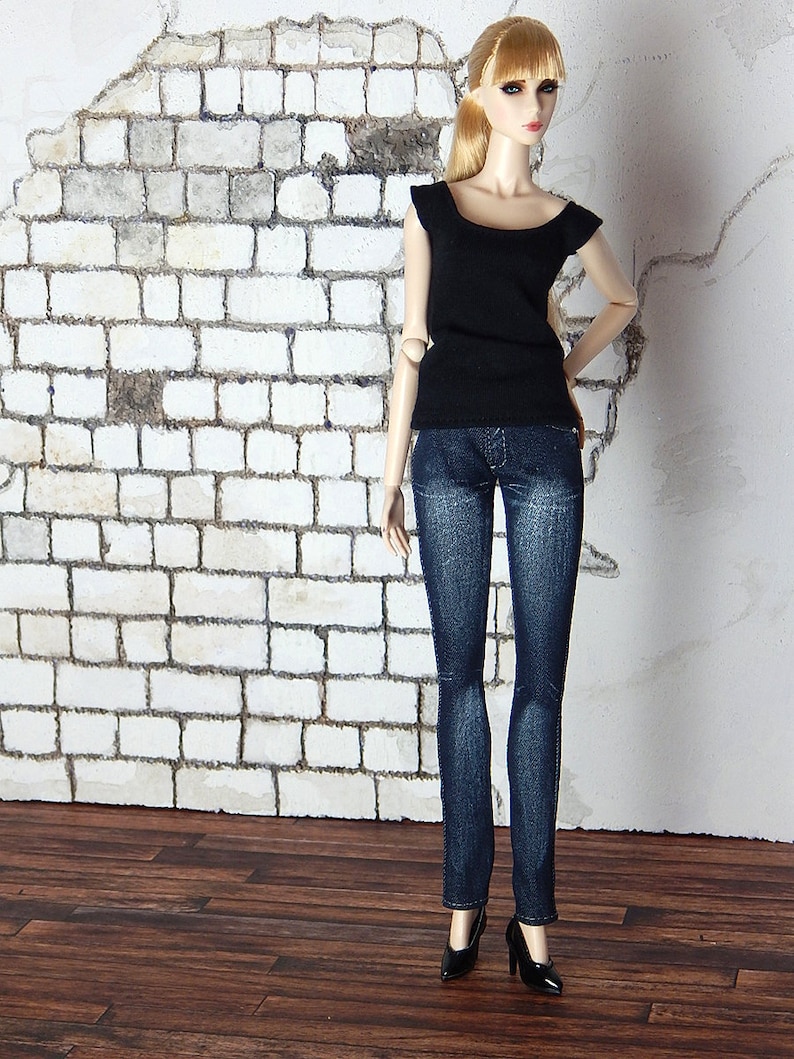 May include: A doll wearing a black sleeveless top and blue jeans. The doll has long blonde hair and is wearing black heels.
