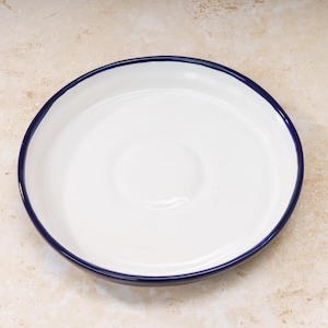 May include: White ceramic plate with a blue rim. The plate is round and has a slightly raised center.