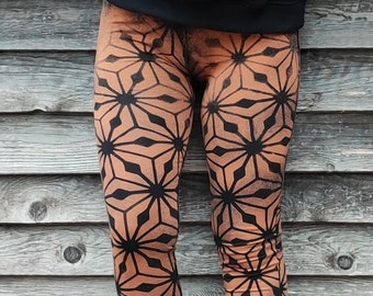 Woman's legging with sacred geometry on leg, cubes patterns bleached with stencils. Mystical symbols for witches and trance festival souls