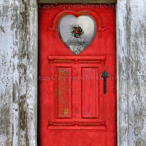 Puede incluir: Una puerta roja en forma de corazón con un panel de ventana roto. La puerta está rodeada de madera desgastada.