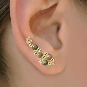 Puede incluir: Pendiente de oreja de oro con cuentas de piedras preciosas verdes y marrones. El pendiente está diseñado para envolverse alrededor de la parte superior de la oreja.