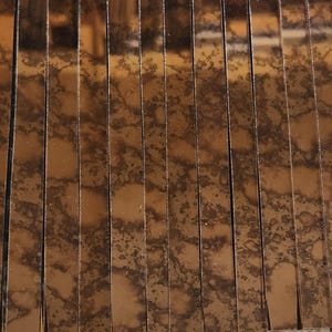 May include: A close-up of a sheet of antique mirror tiles. The tiles are arranged in rows and have a brown, mottled finish.