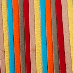 May include: A close-up of a colorful striped fabric with alternating bands of red, orange, yellow, blue, gray, and beige.