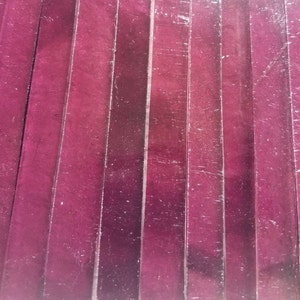 May include: A close-up of a textured, pink, wooden surface with vertical lines. The surface is made of many thin, vertical strips of wood.