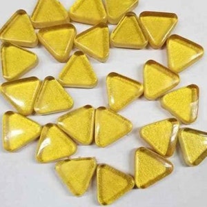 May include: A collection of gold-colored glass triangle tiles. The tiles are arranged in a circular pattern.