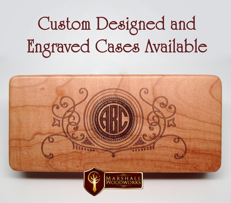 May include: A wooden box with a custom engraved design featuring a monogram of the letters "ABC" in a circle surrounded by decorative flourishes. The box is made by Marshall Woodworks.