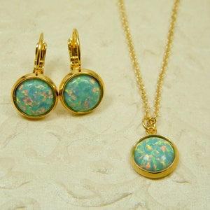 May include: A gold necklace and earrings set with a light blue opal stone pendant and matching earrings.