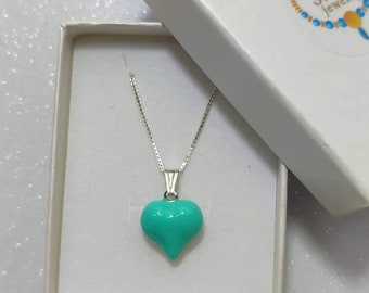 May include: A silver chain necklace with a turquoise heart-shaped pendant in a white box. The box has the text "Sheri Jewelry" on the top.