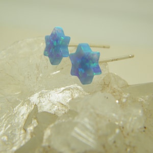 Op de afbeelding: Een paar zilveren oorbelletjes met blauwe opaal sterren.