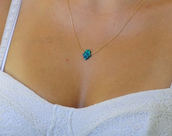 Peut inclure: Un collier en chaîne dorée avec un pendentif main de Hamsa en opale bleue.