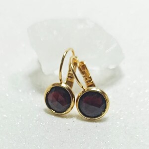 Puede incluir: Un par de pendientes de aro de oro con acentos de piedras preciosas de color rojo oscuro.