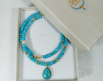 May include: A turquoise and gold necklace with a turquoise pendant in a white gift box. The box has a sticker with the text "Sheri Jewelry".