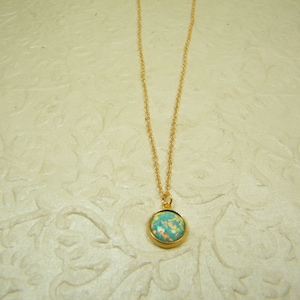 May include: A gold chain necklace with a round, light blue and white opal pendant.