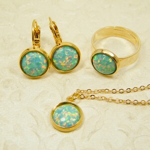 Peut inclure: Un ensemble de bijoux en or comprenant un collier, une bague et des boucles d'oreilles. Chaque pièce est ornée d'une pierre ronde d'opale verte irisée.