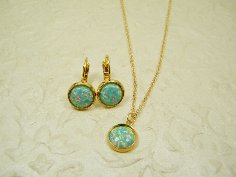 May include: A gold necklace and earrings set with a light blue opal stone pendant and matching earrings.