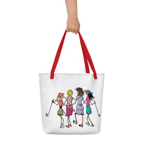May include: White tote bag with red handles featuring a cartoon illustration of four women in colorful outfits holding golf clubs. The women are wearing hats and smiling.