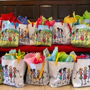 May include: A group of 18 colorful tote bags with a design of women playing golf. The bags are arranged in two rows on a red bench and the floor. The bags are made of canvas and have yellow handles. The design on the bags is a cartoon illustration of women playing golf in a green field. The bags have the words "Friends" printed on them.
