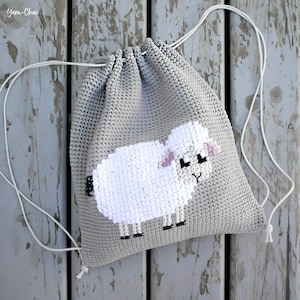 May include: Gray crocheted drawstring bag with a white crocheted sheep design. The bag has white drawstrings.
