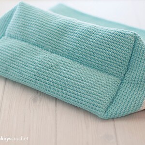 May include: A crocheted tote bag with a striped design in white, gray, and light blue. The bag is made with a textured stitch and has a flat bottom.