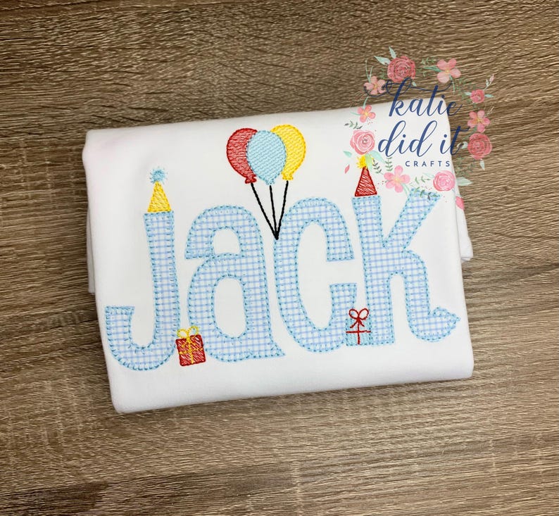 May include: White t-shirt with the name "Jack" embroidered in blue gingham letters. The design includes party hats, balloons, and a gift box, perfect for a birthday celebration. The text "katie did it crafts" is also visible.