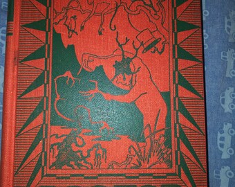 May include: A red book cover with a green border and a starburst design. The cover features an illustration of a man in a top hat and a monkey in a tree. The title of the book is "Doctor Dolittle in the Moon".