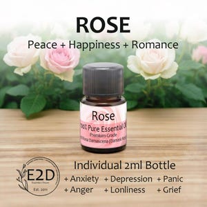 May include: A small glass bottle of rose essential oil with a black cap. The label reads "Rose" and "100% Pure Essential Oil." The image includes text: "Peace + Happiness + Romance" and "Individual 2ml Bottle."