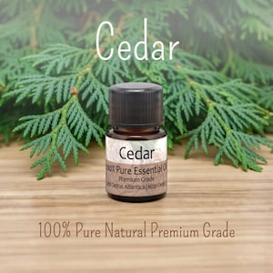 May include: A small brown glass bottle of Cedar 100% Pure Essential Oil with a black cap. The label reads Cedar 100% Pure Essential Oil Premium Grade Cedrus Atlantica. The text 100% Pure Natural Premium Grade is printed below the bottle.