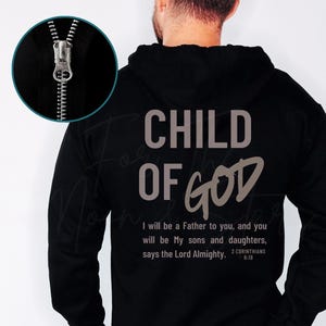 May include: Black hooded sweatshirt with the text "CHILD OF GOD" in gray. Below the text is a Bible verse from 2 Corinthians 6:18. The sweatshirt has a full zipper and a drawstring hood.